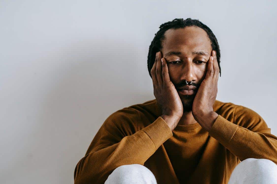 Man sitting with hands on face showing emotional overwhelm and depressive symptoms
