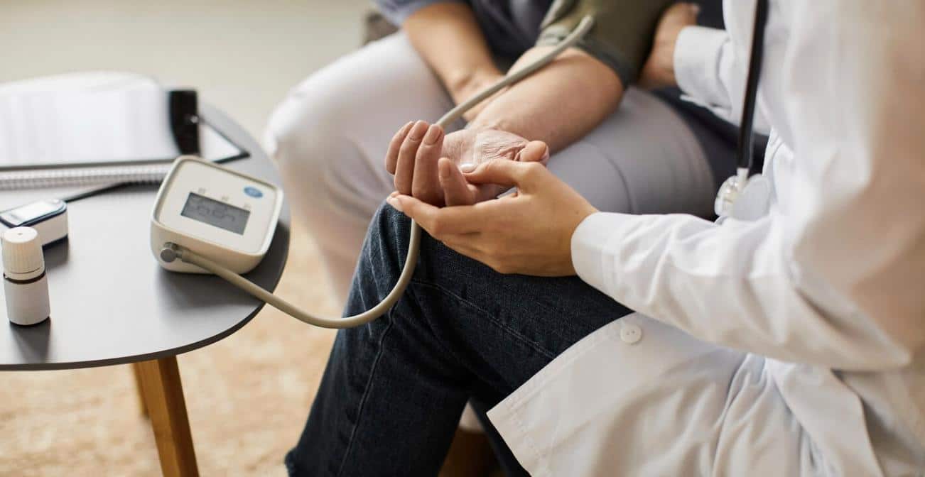 A doctor measuring an elderly patient's blood pressure in clinic setting.