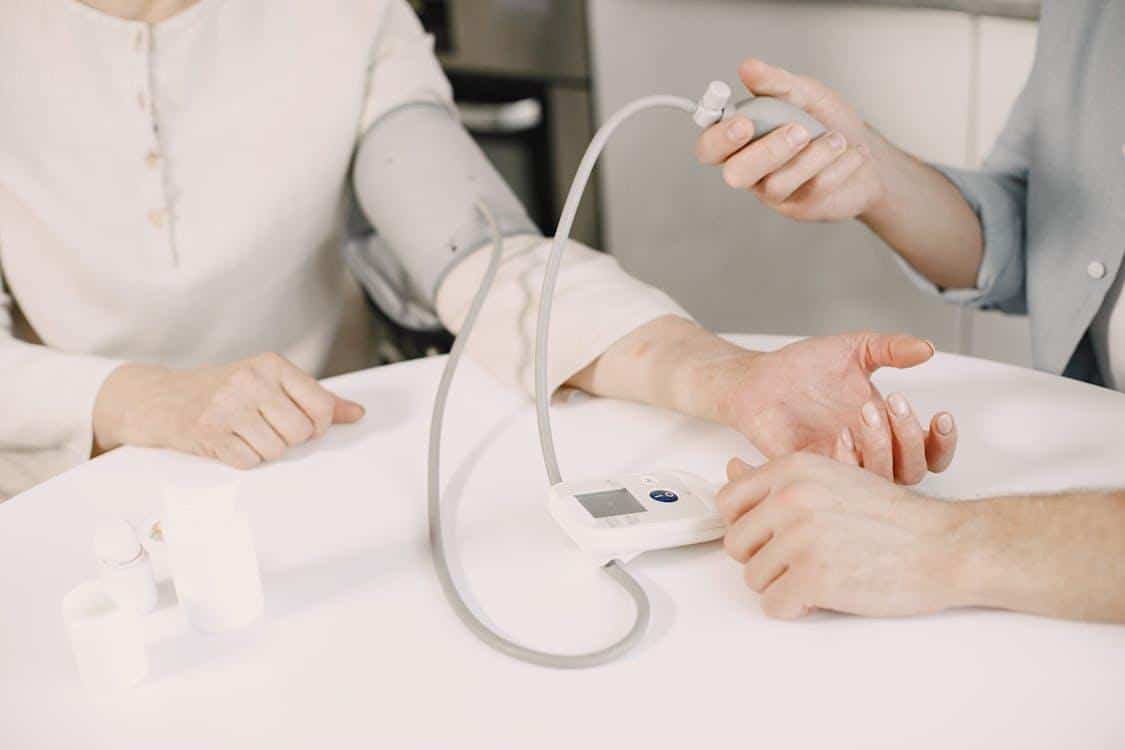 Healthcare professional checking patient's blood pressure using a monitoring device for early detection