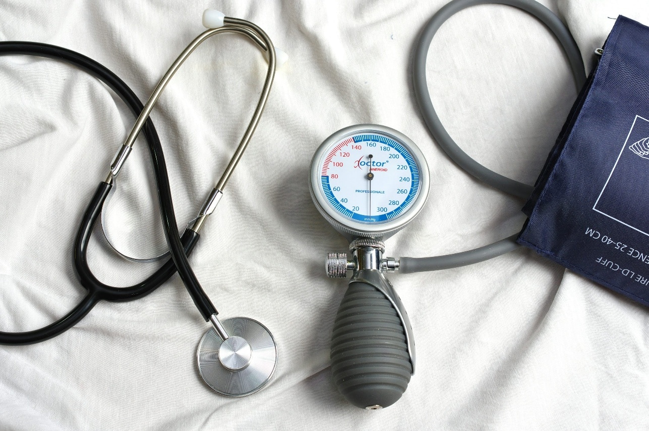 Blood pressure cuff and stethoscope placed on a bed representing home monitoring tools