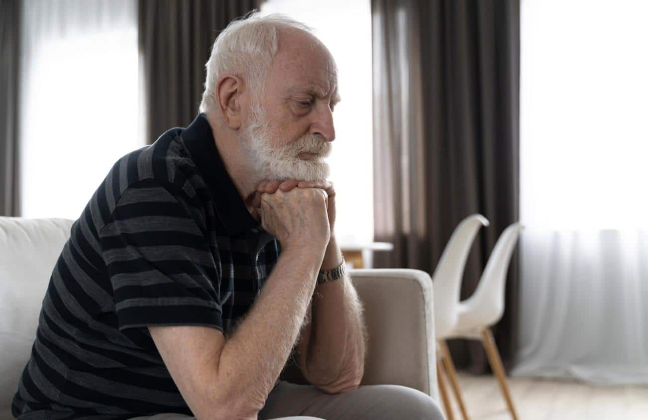 A tired elderly man resting at home with low energy.