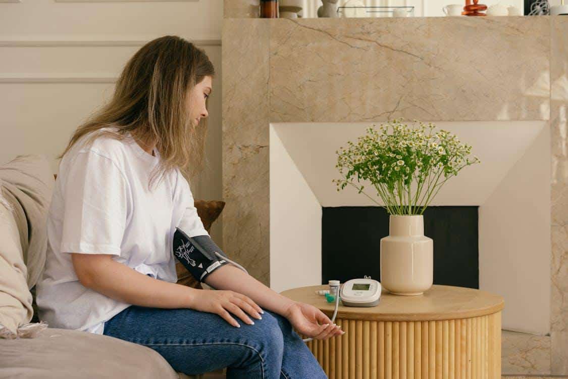 Woman checking blood pressure at home, demonstrating routine monitoring for hypertension