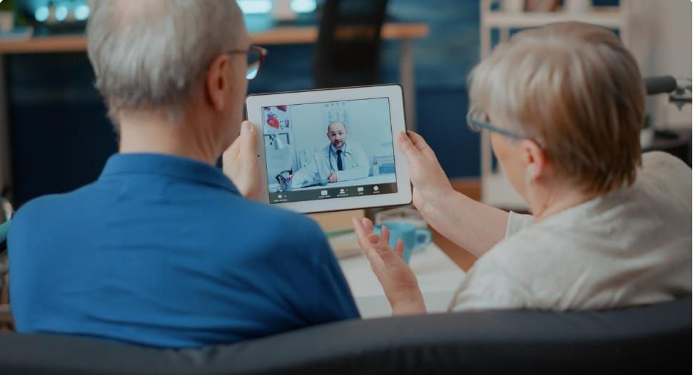 Senior couple attending online medical consultation with doctor using digital tablet for telemedicine caregiver support