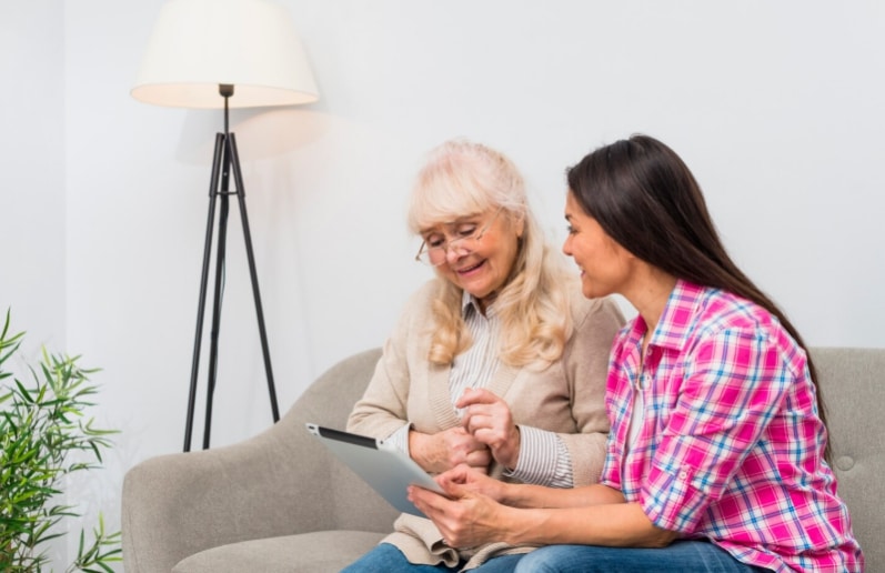 Senior mother and daughter using a digital tablet together representing family caregiver support and FMLA medical leave assistance