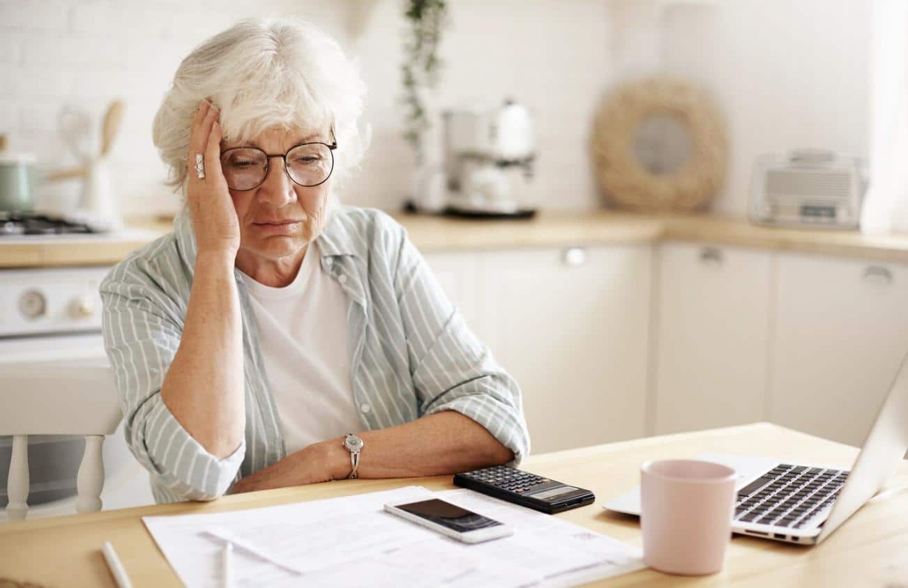 A senior woman sitting at home feeling stressed.