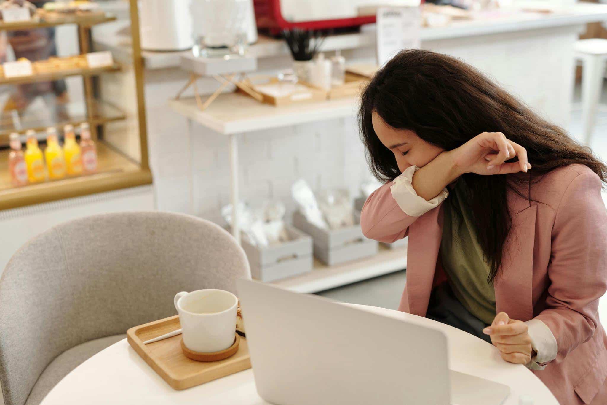 a sick person sneezing into their arm